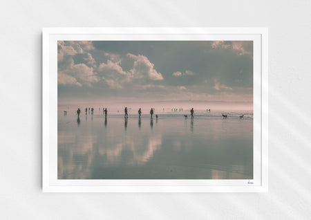 Beach Fever, a colour photographic print  in a white frame depicting the sky and people reflected on Saunton Sands.