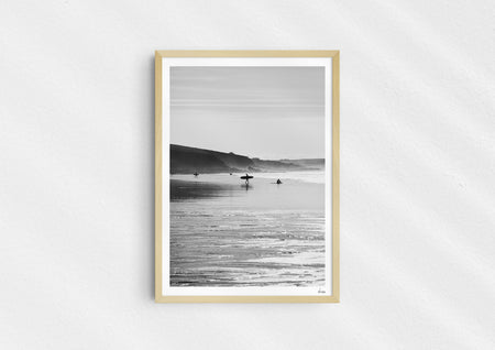 Clear To Land, a black-and-white photo print of surfers on the beach at Polzeath, Cornwall in a wood frame.