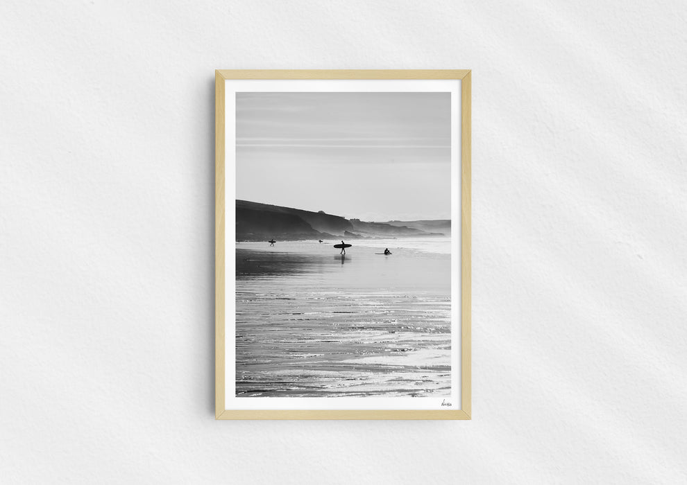 Clear To Land, a black-and-white photo print of surfers on the beach at Polzeath, Cornwall in a wood frame.