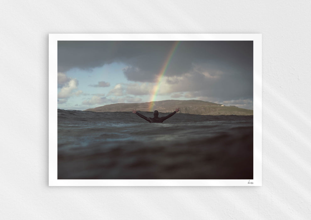 Colours With Colour, a colour photographic print of a surfer saluting a rainbow in Scotland.
