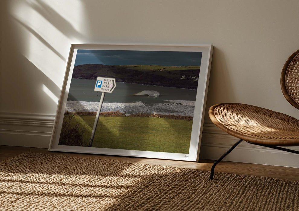 Delivery Bowls, a fine art photo print of a barrelling wave at Croyde Bay in Devon in a frame leaned up against a wall.