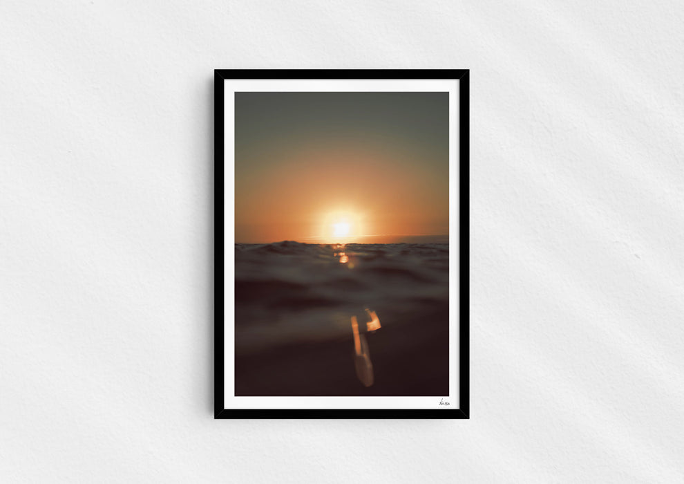 Gold Stripe, a colour photographic print of the sun at the ocean horizon at Croyde Bay, Devon in a black frame.