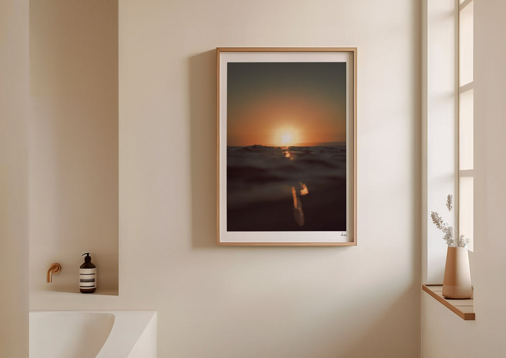 Gold Stripe, a colour photographic print of the sun at the ocean horizon at Croyde Bay, Devon in a frame on a bathroom wall.