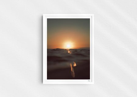 Gold Stripe, a colour photographic print of the sun at the ocean horizon at Croyde Bay, Devon in a white frame.
