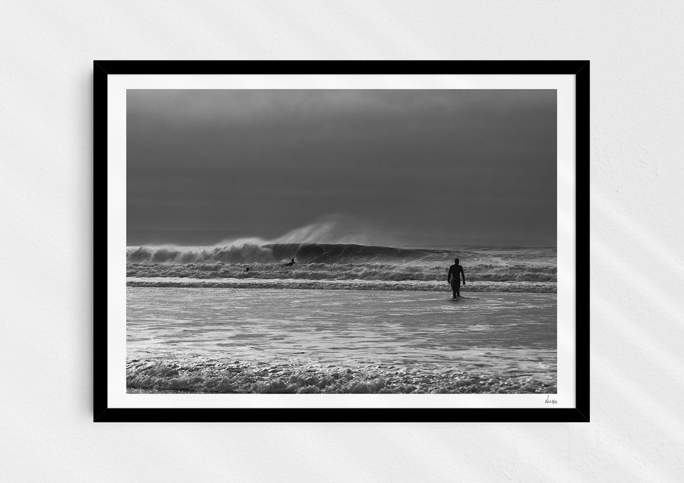 Into the Tempest, a colour photographic print of a surfer facing a breaking wave at Croyde Bay in Devon in a black frame.