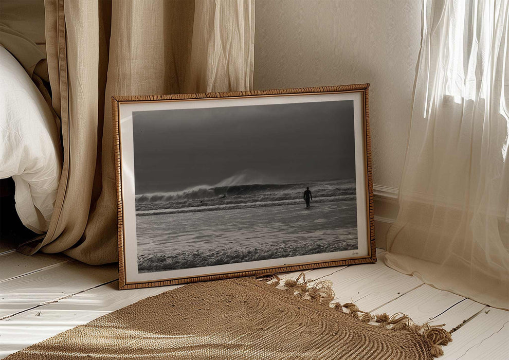 Into the Tempest, a colour photographic print of a surfer facing a breaking wave at Croyde Bay in Devon in a frame in a bedroom.