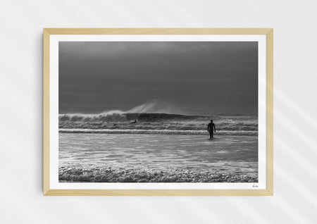 Into the Tempest, a colour photographic print of a surfer facing a breaking wave at Croyde Bay in Devon in a wood frame.