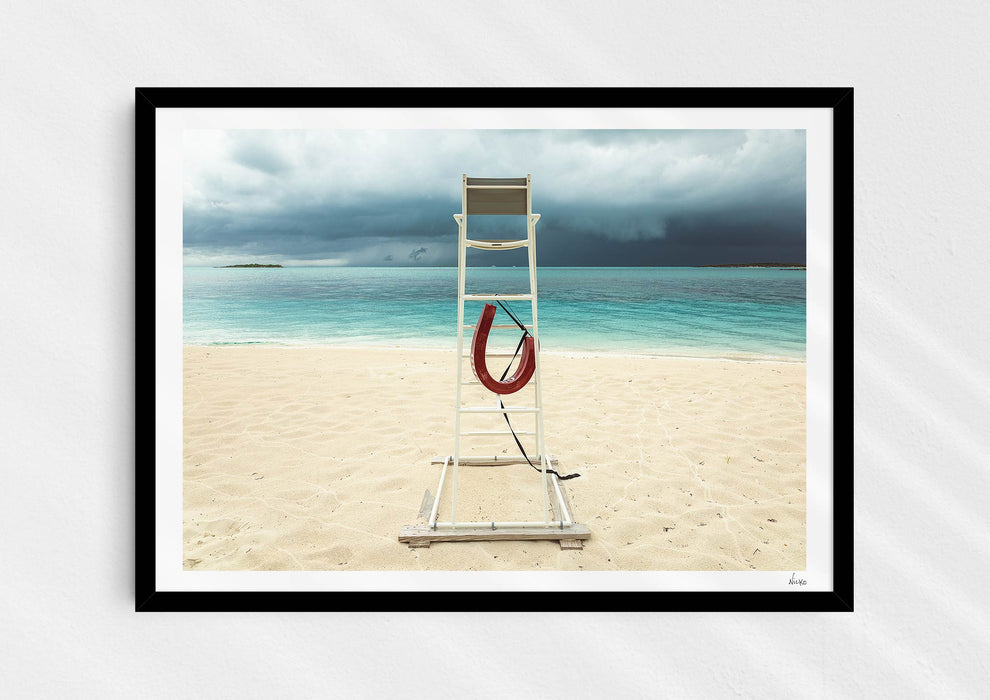 Lifeguard Not Included, a colour photographic print of a lifeguard chair on a white sandy beach in a black frame.