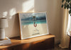 A framed print in a room of Lifeguard Not Included, a colour photograph of a lifeguard chair on a white sandy beach.