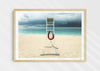 Lifeguard Not Included, a colour photographic print of a lifeguard chair on a white sandy beach. in a wood frame.