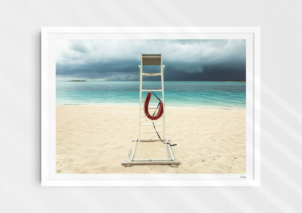 Lifeguard Not Included, a colour photographic print of a lifeguard chair on a white sandy beach in a white frame.