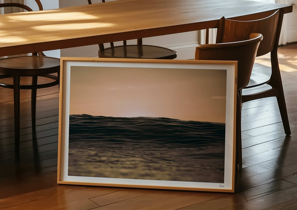 A framed print in a room of Light Life, a colour photograph depicting dusk over calm ocean at Woolacombe, Devon.
