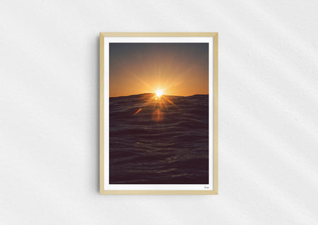 Light in the Deep, a colour photographic print of the sun on the ocean horizon at Porthtowan, Cornwall in a wood frame.
