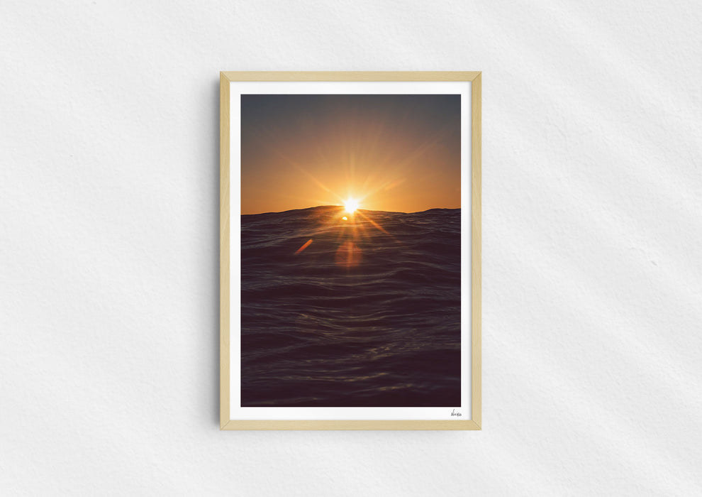 Light in the Deep, a colour photographic print of the sun on the ocean horizon at Porthtowan, Cornwall in a wood frame.
