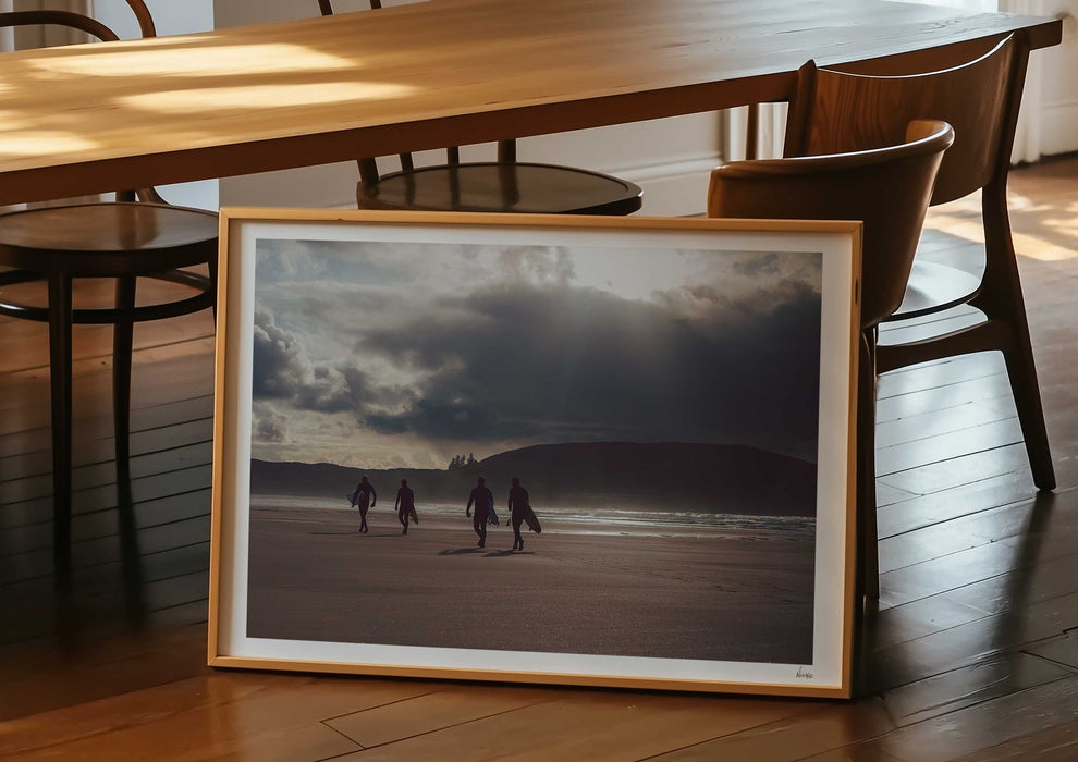 Mutual People, a colour photographic print of surfers walking across sand in northern Scotland in a frame in a dining room.