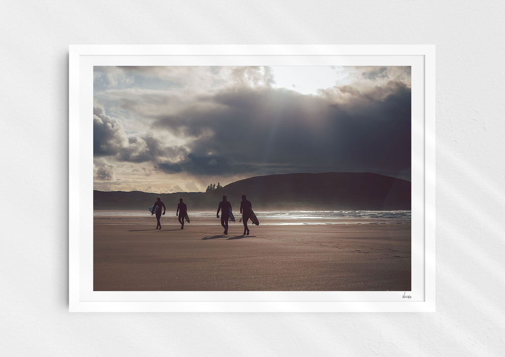 Mutual People, a colour photographic print of surfers walking across sand in northern Scotland in a white frame.