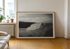 Nowhere To Hide, a black-and-white photo print of a surfer on a wave in Porthtowan, Cornwall in a frame leaning against a wall.