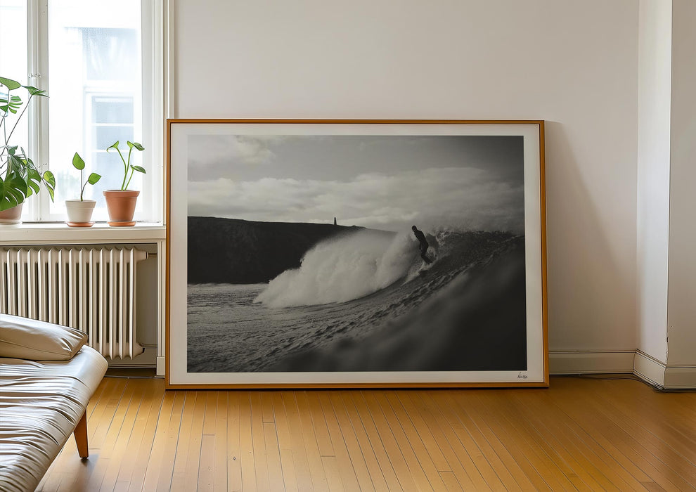 Nowhere To Hide, a black-and-white photo print of a surfer on a wave in Porthtowan, Cornwall in a frame leaning against a wall.