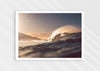 photograph print of a wave at sunrise breaking on a beach with a cliff in the background.