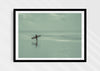Sea Wanderer, a colour photographic print of a surfer walking across Saunton Sands, Devon in a black frame.