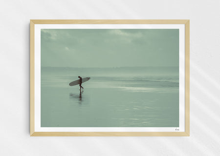 Sea Wanderer, a colour photographic print of a surfer walking across Saunton Sands, Devon in a wood frame.