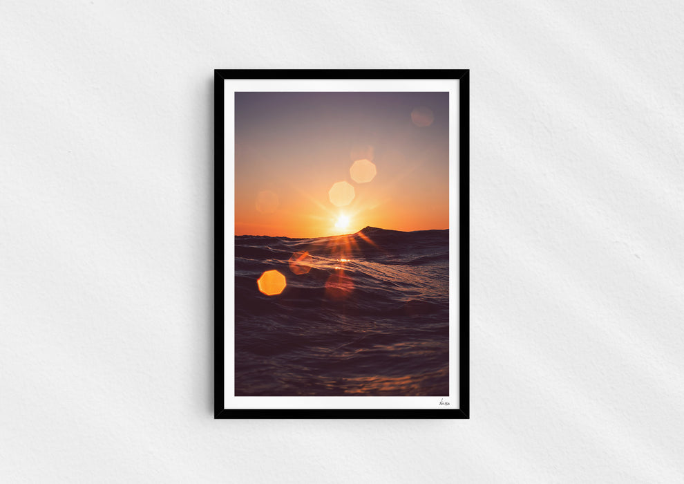 Solar Flare, a colour photographic print of sunlight on the ocean at Porthtowan, Cornwall in a black frame.