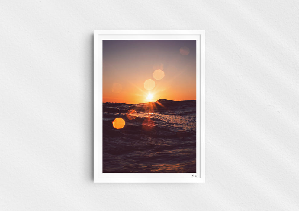 Solar Flare, a colour photographic print of sunlight on the ocean at Porthtowan, Cornwall in a white frame.