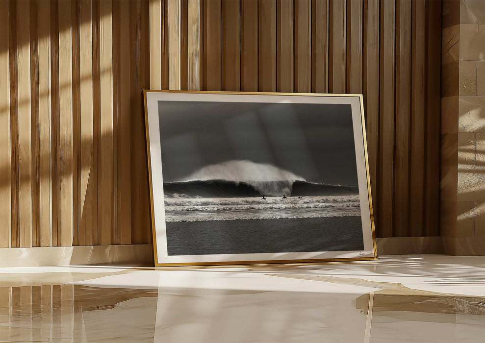 Untamable, a fine art photographic print depicting a barrelling wave with spray at Croyde Bay in Devon in a frame propped up against a wall.
