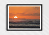 Watching Her Sink, a colour photographic print of surfers at sunset at Croyde Bay, Devon in a black frame.
