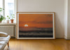 Watching Her Sink, a colour photographic print of surfers at sunset at Croyde Bay, Devon in a frame leaning against a wall.