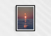 We’ll Meet Again, a colour photographic print of a bird and sunset over a calm ocean in a black frame.