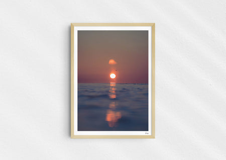 We’ll Meet Again, a colour photographic print of a bird and sunset over a calm ocean in a wood frame.