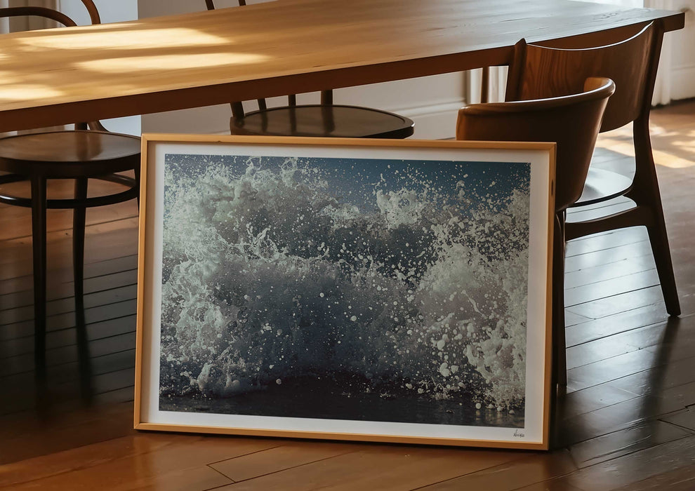 A framed print in a room of What We Sea, a colour photograph of white water from a sea-level perspective.