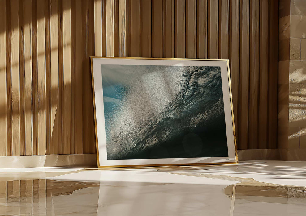 Wild Seductive, a colour photographic print of water droplets suspended over a wave in the Azores in a frame leaning against a wall.